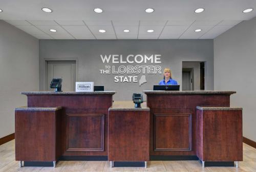 a woman standing at a podium in a lobby at Hampton Inn Bath - Brunswick Area , ME in Bath