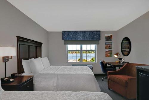 een hotelkamer met een bed, een stoel en een raam bij Hampton Inn Bath - Brunswick Area , ME in Bath