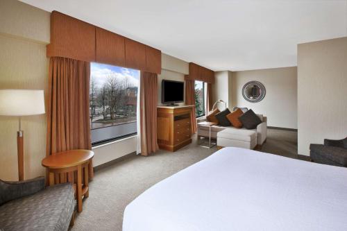 um quarto de hotel com uma cama, um sofá e uma janela em Hilton Garden Inn Portland Downtown Waterfront em Portland
