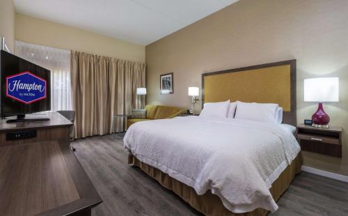 ein Hotelzimmer mit einem Bett und einem Flachbild-TV in der Unterkunft Hampton Inn Freeport/Brunswick in Freeport