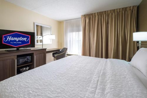 a hotel room with a bed and a flat screen tv at Hampton Inn Freeport/Brunswick in Freeport