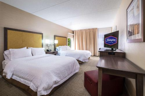 a hotel room with two beds and a flat screen tv at Hampton Inn Freeport/Brunswick in Freeport