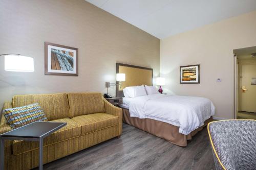 a hotel room with a bed and a couch at Hampton Inn Freeport/Brunswick in Freeport