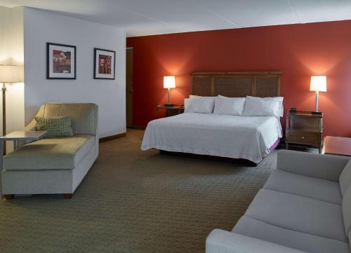 サウスポートランドにあるHampton Inn Portland-Airportのベッド1台と椅子2脚が備わるホテルルームです。