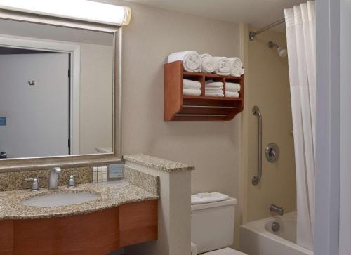 a bathroom with a sink and a toilet and a mirror at Hampton Inn Portland-Airport in South Portland
