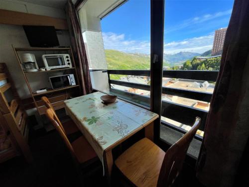 une table et des chaises dans une pièce avec une grande fenêtre dans l'établissement Studio 18 m² avec balcon, animaux permis - FR-1-452-236, aux Menuires