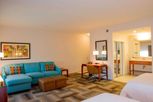 ein Wohnzimmer mit einem blauen Sofa und einem Schreibtisch in der Unterkunft Hampton Inn & Suites Riverside/Corona East in Riverside