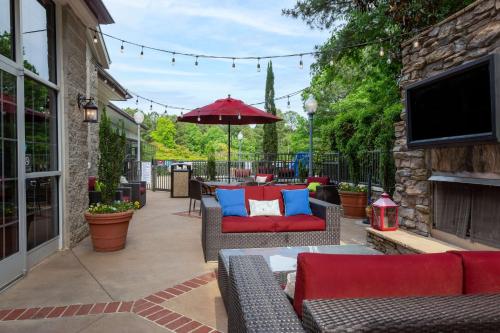 a patio with couches and an umbrella and a tv at Hampton Inn & Suites Raleigh/Cary I-40 (PNC Arena) in Cary