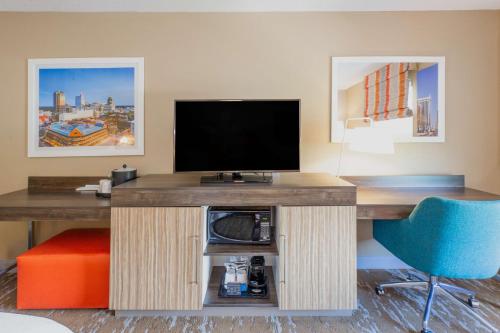 a desk with a television and a blue chair at Hampton Inn & Suites Raleigh Cary Lenovo Center in Cary