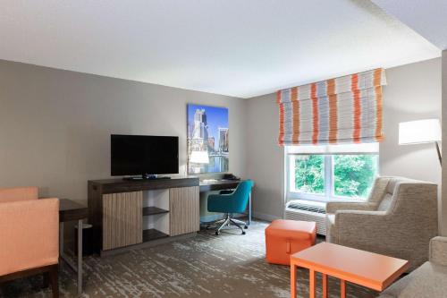 a small living room with a television and a chair at Hampton Inn & Suites Raleigh Cary Lenovo Center in Cary