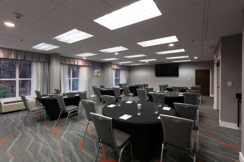 a conference room with tables and chairs and a screen at Hampton Inn & Suites Raleigh Cary Lenovo Center in Cary