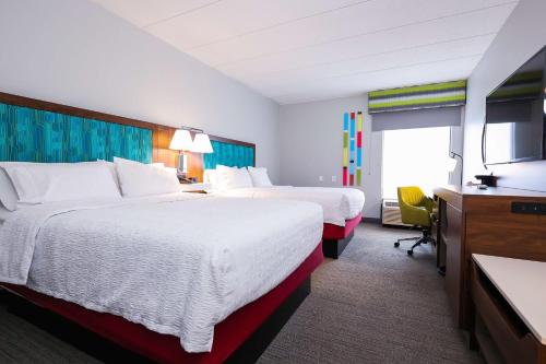 a hotel room with two beds and a flat screen tv at Hampton Inn Rehoboth Beach in Rehoboth Beach