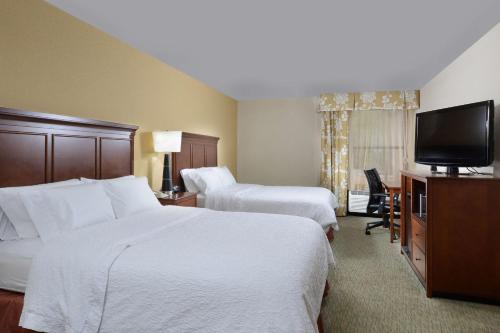 a hotel room with two beds and a flat screen tv at Hampton Inn Raleigh/Durham Airport in Morrisville