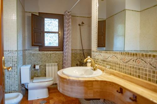 W łazience znajduje się umywalka, toaleta i lustro. w obiekcie Apartamentos La Güertona w mieście Sardalla