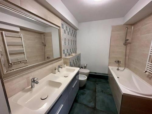 une salle de bain avec deux lavabos et une baignoire et des toilettes dans l'établissement Apartament Sianna, à Mamaia