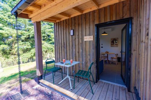 a porch of a wooden cabin with a table and chairs at Lodges de Lemptégy in Saint-Ours