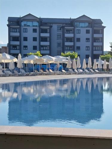 un hôtel avec une piscine dotée de parasols et de chaises dans l'établissement Apartmani Martenovic 1, à Vrnjačka Banja