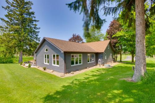 a gray house with a tree in the yard at Spacious Massillon Log Cabin with Fire Pit! in Massillon
