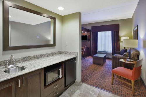 a hotel room with a sink and a living room at Hampton Inn Brockport in Brockport