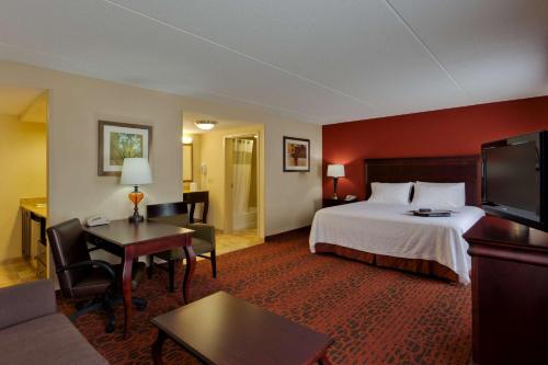 a hotel room with a bed and a living room at Hampton Inn Rochester-Webster in Webster