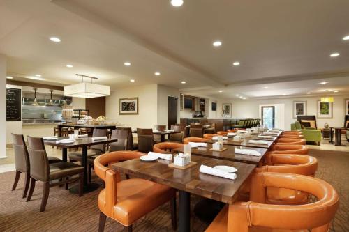 a restaurant with wooden tables and leather chairs at Hilton Garden Inn Rochester/Pittsford in Bushnell Basin