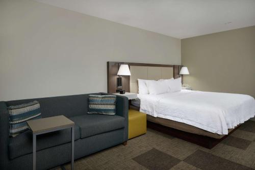 a hotel room with a bed and a couch at Hampton Inn & Suites Rogers in Rogers