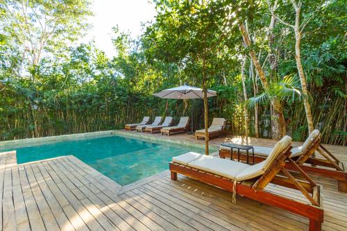 a swimming pool with lounge chairs and an umbrella at Amazing 3Br & Private Patio With Pool in Tulum in Tulum