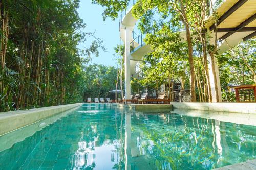 a swimming pool in front of a building with trees at Amazing 3Br & Private Patio With Pool in Tulum in Tulum