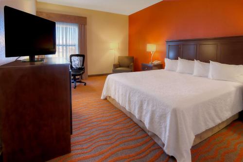 a hotel room with a bed and a flat screen tv at Hampton Inn Russellville in Russellville