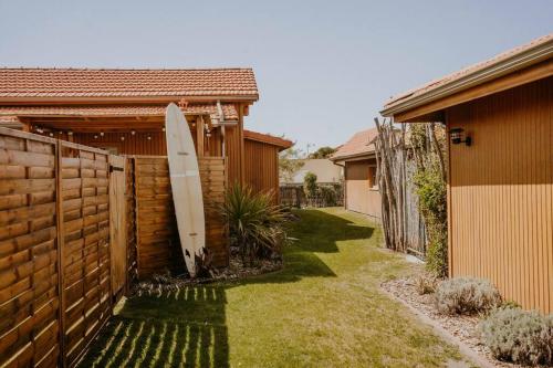 une planche de surf penchée contre une clôture à côté d'une maison dans l'établissement La cabane de Mamie classée 4 étoiles à 150m de la plage 2 chambres 3 lits, à Biscarrosse-Plage