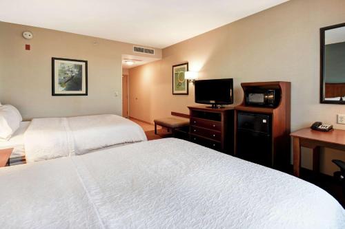 a hotel room with two beds and a flat screen tv at Hampton Inn & Suites Folsom in Folsom