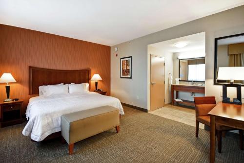 a hotel room with a large bed and a desk and a desk at Hampton Inn & Suites Folsom in Folsom