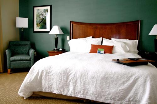 a bedroom with a large white bed and a chair at Hampton Inn & Suites Folsom in Folsom
