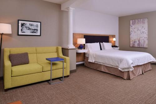 Hampton Inn & Suites Woodland-Sacramento Area في وودلاند: غرفة فندق بسرير واريكة صفراء