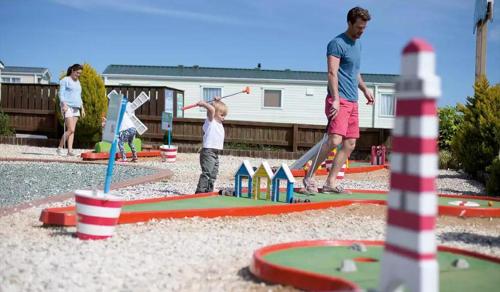 a man and a child playing in a playground at Blue Dolphin Holiday Park in Gristhorpe