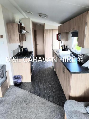 a small kitchen with wooden cabinets and a sink at Blue Dolphin Holiday Park in Gristhorpe