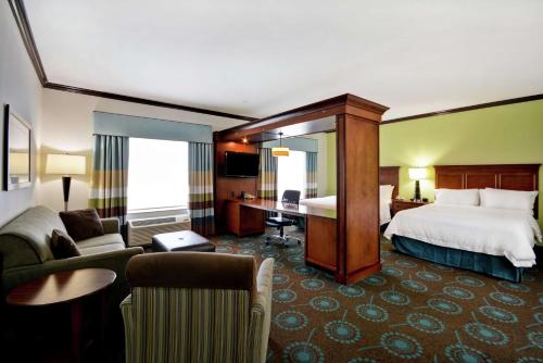 サンアントニオにあるHampton Inn & Suites San Antonio/Northeast I-35のベッドとデスクが備わるホテルルームです。