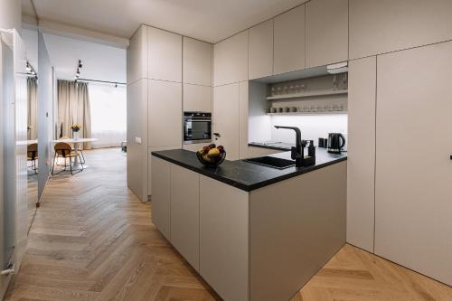 uma cozinha com armários brancos e um balcão preto em Cherry Apartment em Bratislava