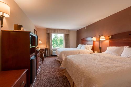 a hotel room with two beds and a flat screen tv at Hampton Inn Goshen in Goshen