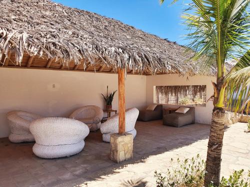a patio with chairs and a thatch roof at Oasis de Vichayito in Vichayito