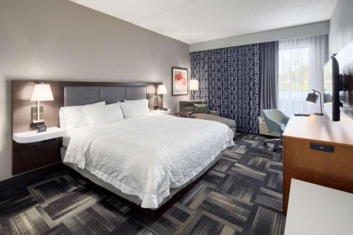 a hotel room with a large bed and a desk at Hampton Inn Louisville Northeast in Louisville