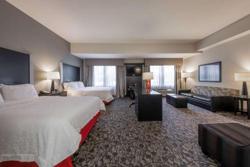 a hotel room with two beds and a couch at Hampton Inn & Suites DuPont in DuPont