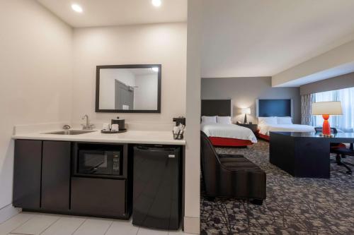 a hotel room with a sink and a room with a bed at Hampton Inn & Suites DuPont in DuPont