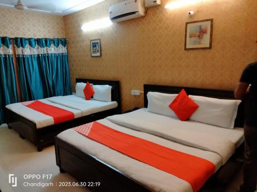 a hotel room with two beds with red and white pillows at Hotel Diamond Ring Chandigarh in Chandīgarh