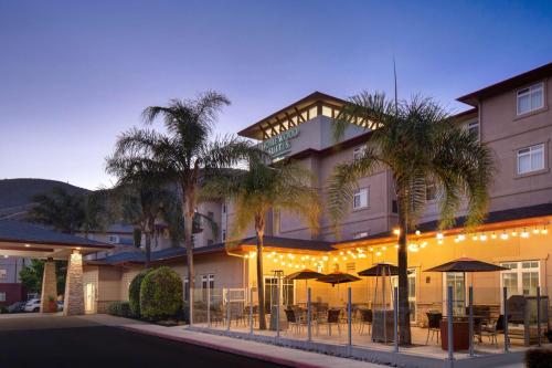 a hotel with tables and umbrellas in front of it at Homewood Suites by Hilton San Francisco Airport North California in Brisbane