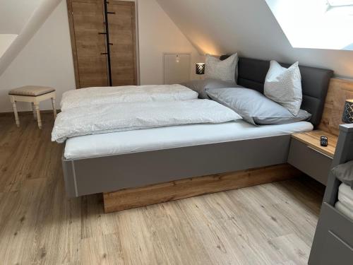 a bedroom with a bed with white sheets and wood floors at Im Kurpark in Bad Ischl