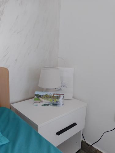 a white bedside table with a lamp on it at Vila Milica in Kladovo