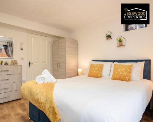 a bedroom with a large white bed with orange pillows at Bright and Cosy Studio Apartment by Jesswood Properties Short Lets With Free Parking Near M1 & Luton Airport in Luton