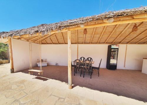 a patio with a table and chairs under a thatched roof at Oasis de Vichayito in Vichayito