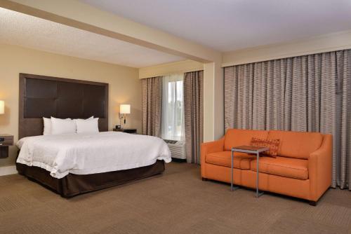 um quarto de hotel com uma cama e uma cadeira laranja em Hampton Inn South Hill em South Hill